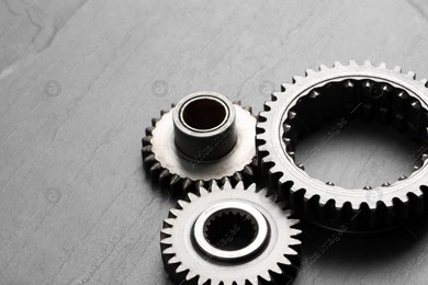 Different stainless steel gears on grey background, space for text Photo of Different stainless steel gears on grey background, space for text