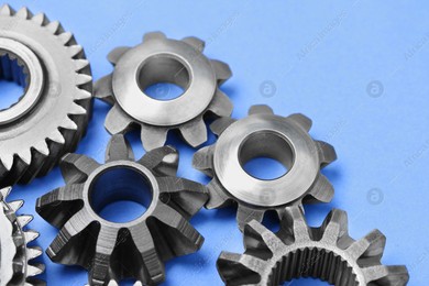 Different stainless steel gears on light blue background, closeup Photo of Different stainless steel gears on light blue background, closeup