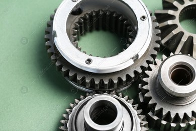 Different stainless steel gears on light green background, closeup Photo of Different stainless steel gears on light green background, closeup
