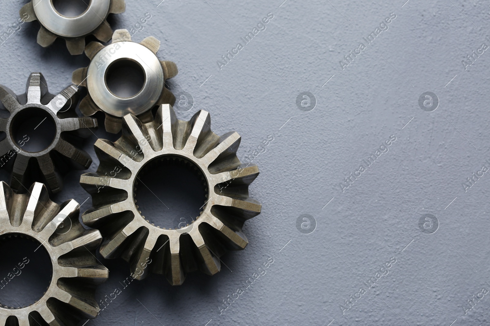 Different stainless steel gears on grey background, flat lay. Space for text Photo of Different stainless steel gears on grey background, flat lay. Space for text