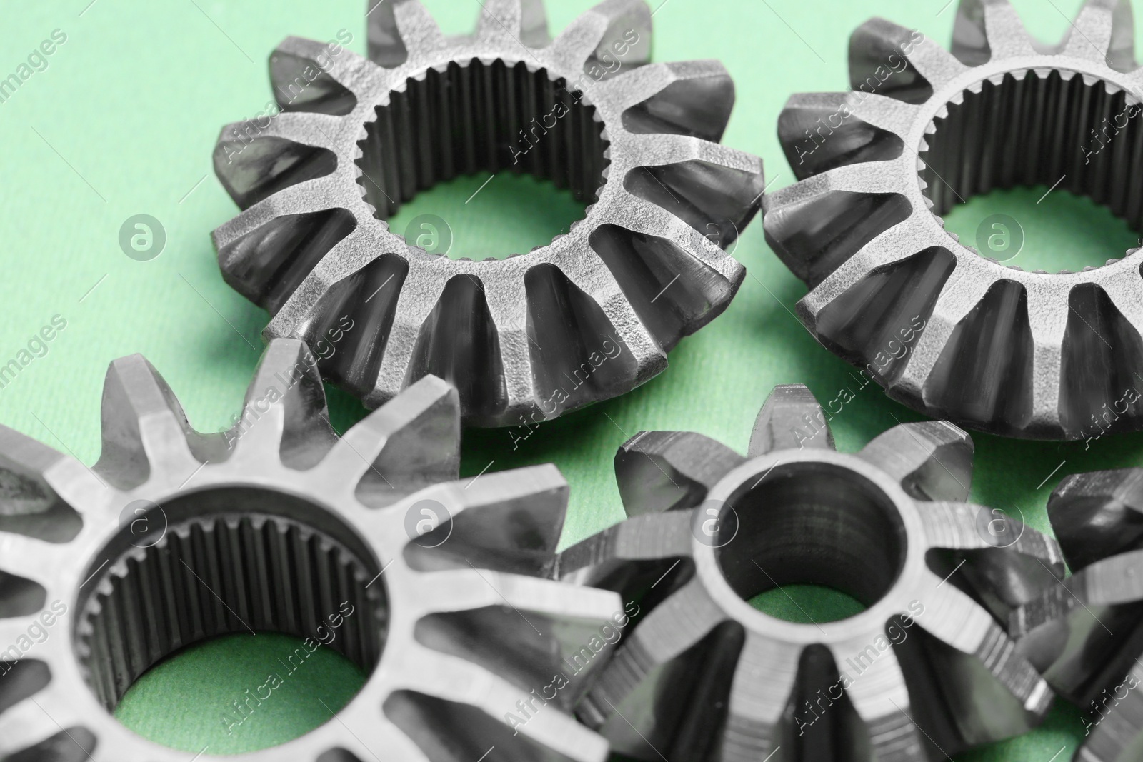 Different stainless steel gears on light green background, closeup Photo of Different stainless steel gears on light green background, closeup