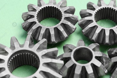 Different stainless steel gears on light green background, closeup Photo of Different stainless steel gears on light green background, closeup