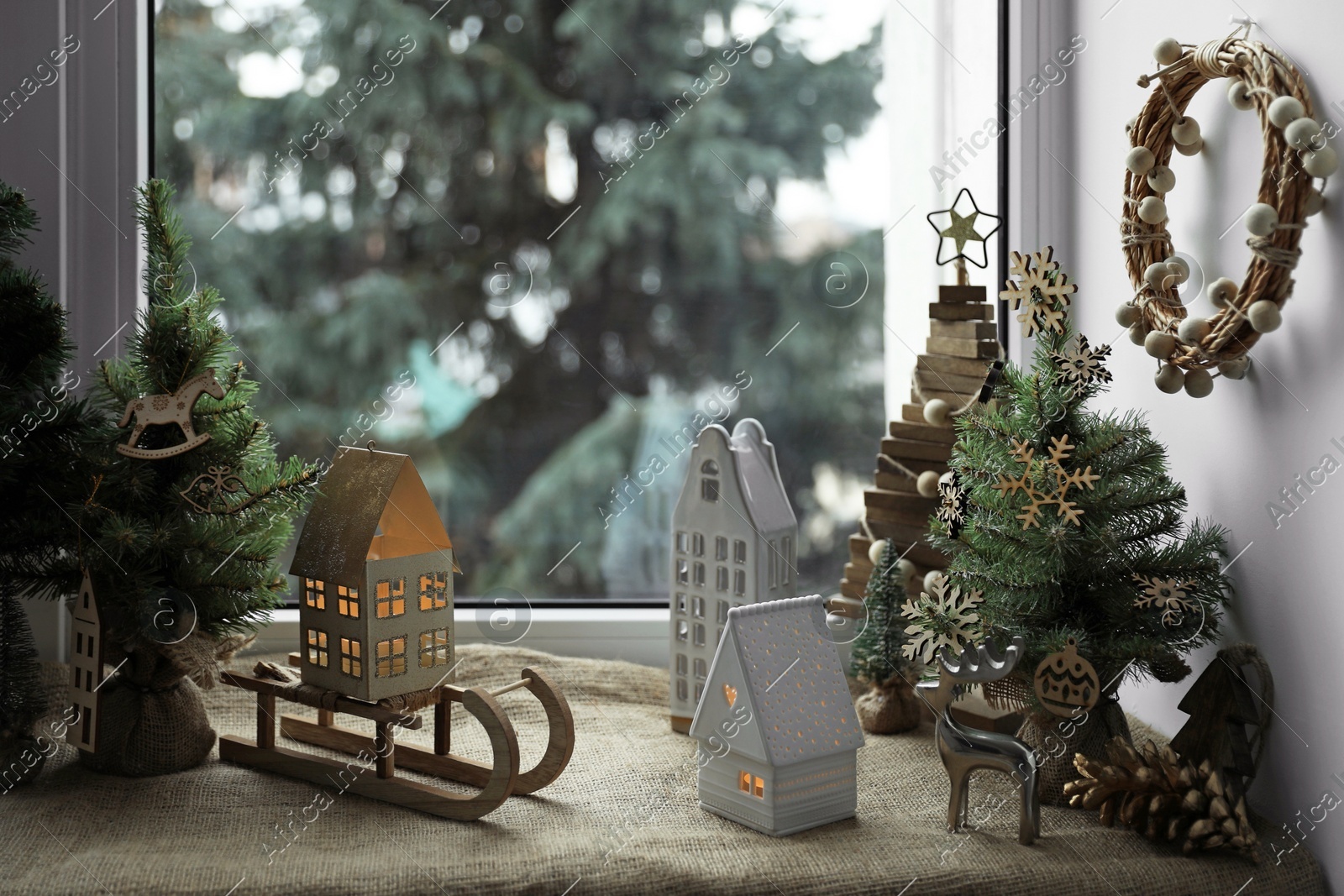 Many beautiful Christmas decorations and small fir trees on window sill indoors Photo of Many beautiful Christmas decorations and small fir trees on window sill indoors