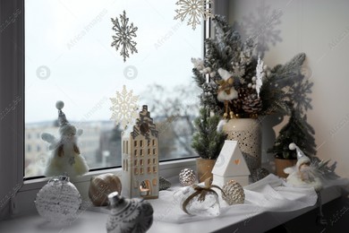Many beautiful Christmas decorations and fir trees on window sill indoors Photo of Many beautiful Christmas decorations and fir trees on window sill indoors
