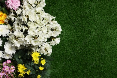 Different beautiful flowers on green grass, flat lay. Space for text Photo of Different beautiful flowers on green grass, flat lay. Space for text