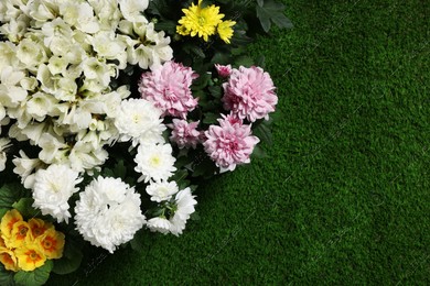 Different beautiful flowers on green grass, flat lay. Space for text Photo of Different beautiful flowers on green grass, flat lay. Space for text
