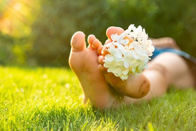 Teenage girl with beautiful hortensia flowers lying on green grass outdoors, closeup Photo of Teenage girl with beautiful hortensia flowers lying on green grass outdoors, closeup