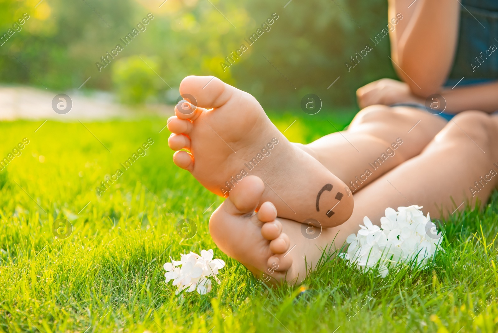 Teenage girl with beautiful hortensia flowers and smiling face drawn on heel outdoors, closeup. Space for text Photo of Teenage girl with beautiful hortensia flowers and smiling face drawn on heel outdoors, closeup. Space for text