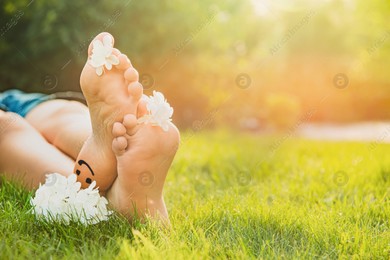 Teenage girl with beautiful hortensia flowers lying on green grass outdoors, closeup. Space for text Photo of Teenage girl with beautiful hortensia flowers lying on green grass outdoors, closeup. Space for text