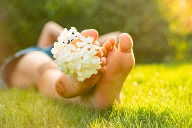 Teenage girl with beautiful hortensia flowers lying on green grass outdoors, closeup Photo of Teenage girl with beautiful hortensia flowers lying on green grass outdoors, closeup