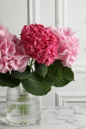 Vase with beautiful hortensia flowers on white marble table Photo of Vase with beautiful hortensia flowers on white marble table