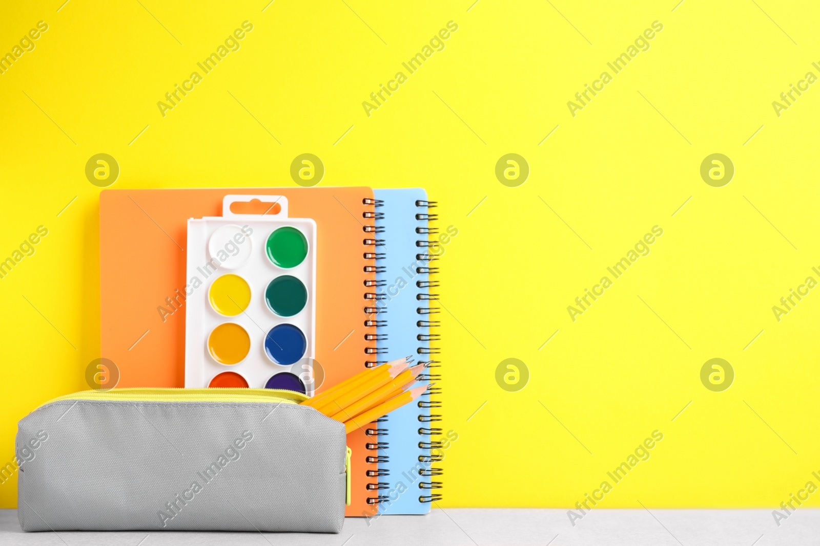 Different school stationery on white table against yellow background, space for text. Back to school Photo of Different school stationery on white table against yellow background, space for text. Back to school