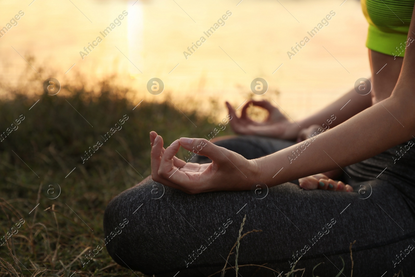 Woman meditating near river at sunset, closeup. Space for text Photo of Woman meditating near river at sunset, closeup. Space for text