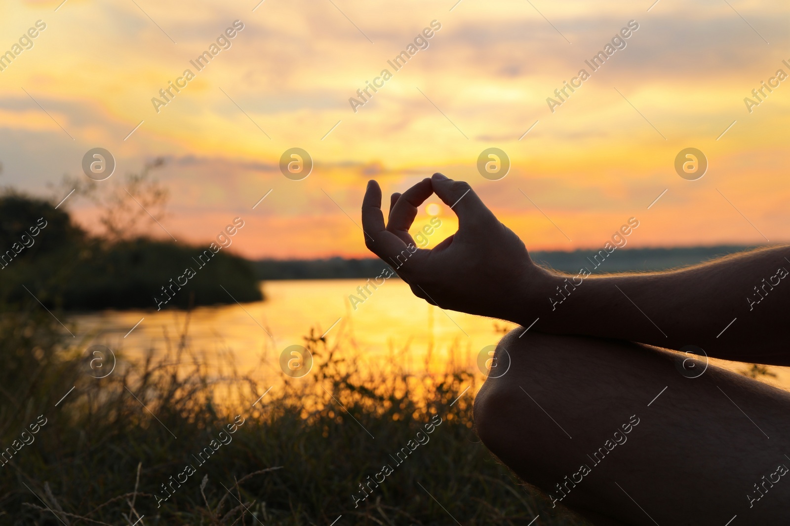 Man meditating near river at sunset, closeup. Space for text Photo of Man meditating near river at sunset, closeup. Space for text