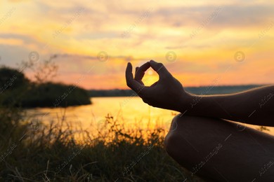 Man meditating near river at sunset, closeup. Space for text Photo of Man meditating near river at sunset, closeup. Space for text