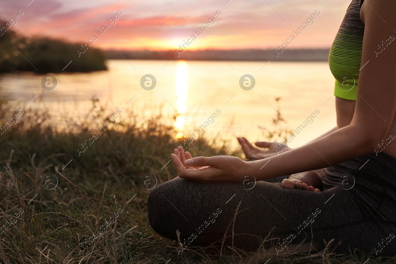 Woman meditating near river at sunset, closeup. Space for text Photo of Woman meditating near river at sunset, closeup. Space for text