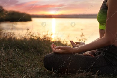 Woman meditating near river at sunset, closeup. Space for text Photo of Woman meditating near river at sunset, closeup. Space for text