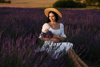 Beautiful young woman with bouquet sitting in lavender field at sunset Photo of Beautiful young woman with bouquet sitting in lavender field at sunset