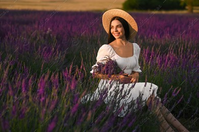 Beautiful young woman with bouquet sitting in lavender field at sunset Photo of Beautiful young woman with bouquet sitting in lavender field at sunset