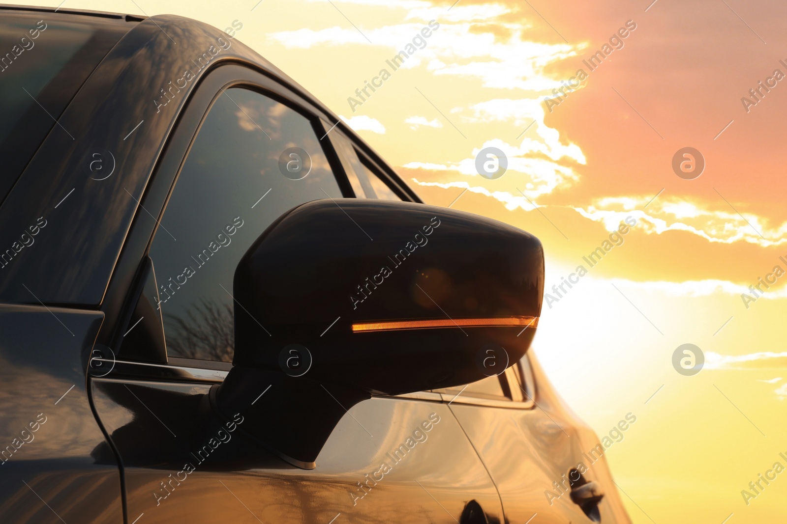 Black modern car outdoors at sunset, closeup of side view mirror Photo of Black modern car outdoors at sunset, closeup of side view mirror