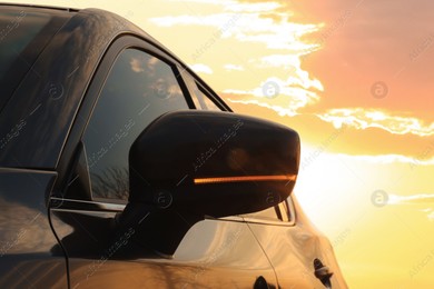 Black modern car outdoors at sunset, closeup of side view mirror Photo of Black modern car outdoors at sunset, closeup of side view mirror