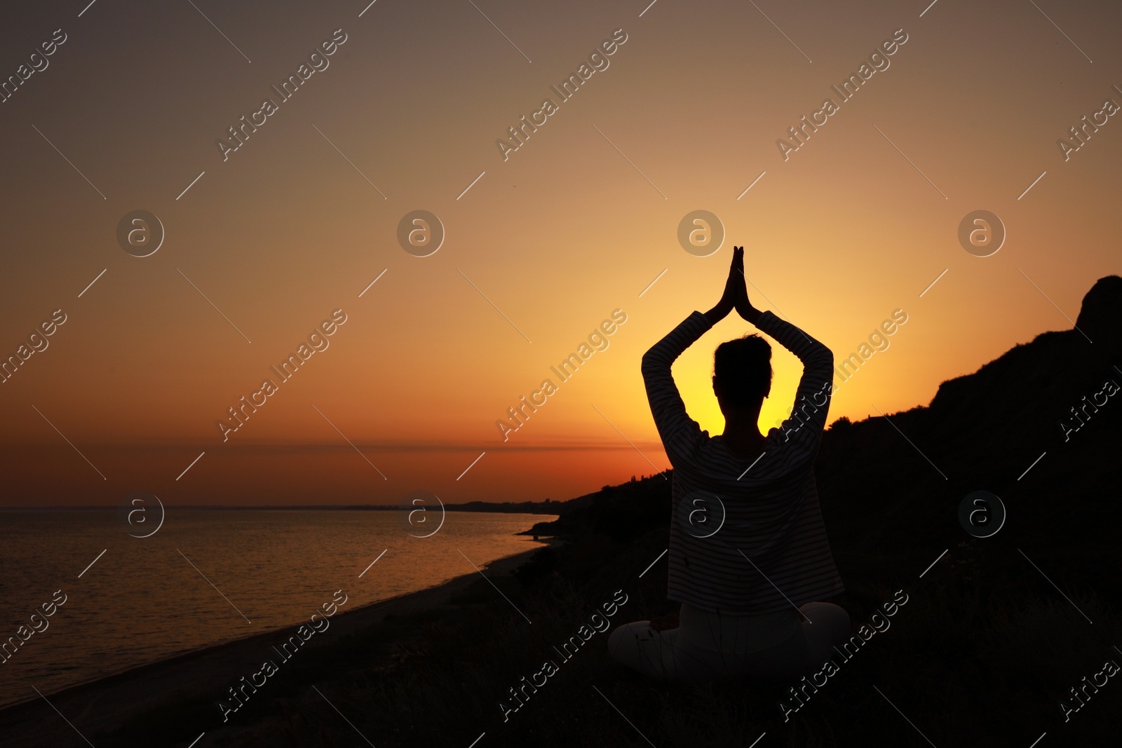 Woman meditating near sea at sunset, back view. Space for text Photo of Woman meditating near sea at sunset, back view. Space for text
