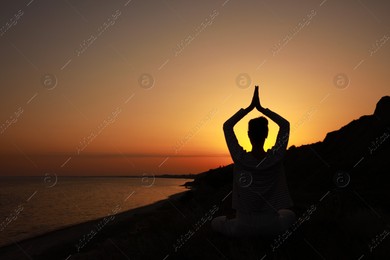 Woman meditating near sea at sunset, back view. Space for text Photo of Woman meditating near sea at sunset, back view. Space for text
