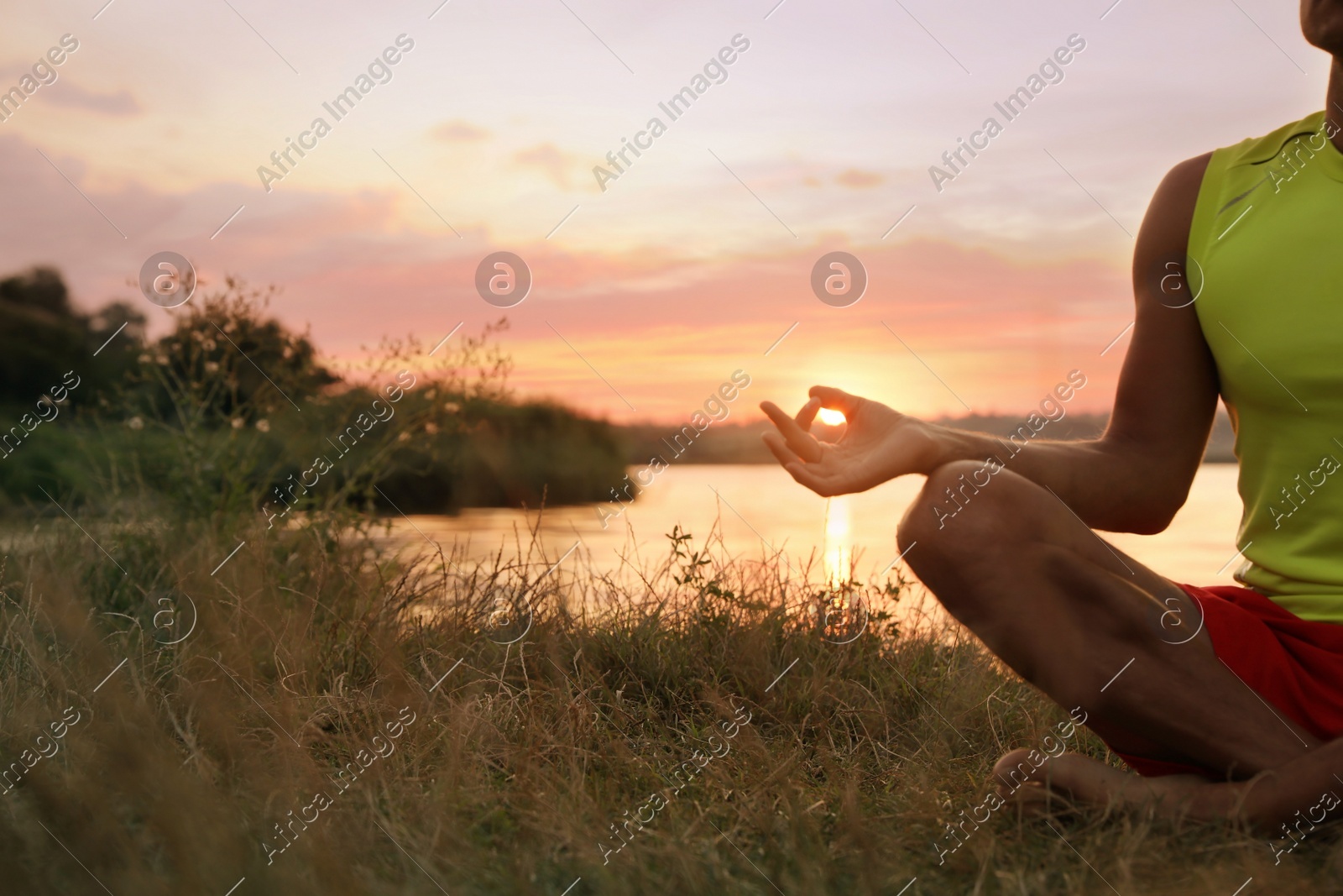 Man meditating near river at sunset, closeup. Space for text Photo of Man meditating near river at sunset, closeup. Space for text