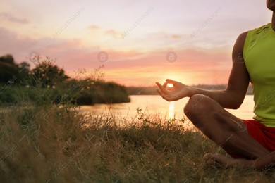 Man meditating near river at sunset, closeup. Space for text Photo of Man meditating near river at sunset, closeup. Space for text