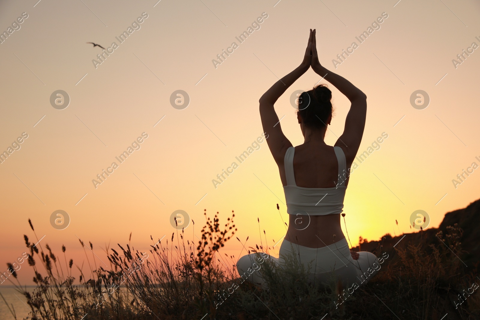 Woman meditating outdoors at sunset, back view. Space for text Photo of Woman meditating outdoors at sunset, back view. Space for text