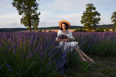 Beautiful young woman sitting in lavender field at sunset Photo of Beautiful young woman sitting in lavender field at sunset