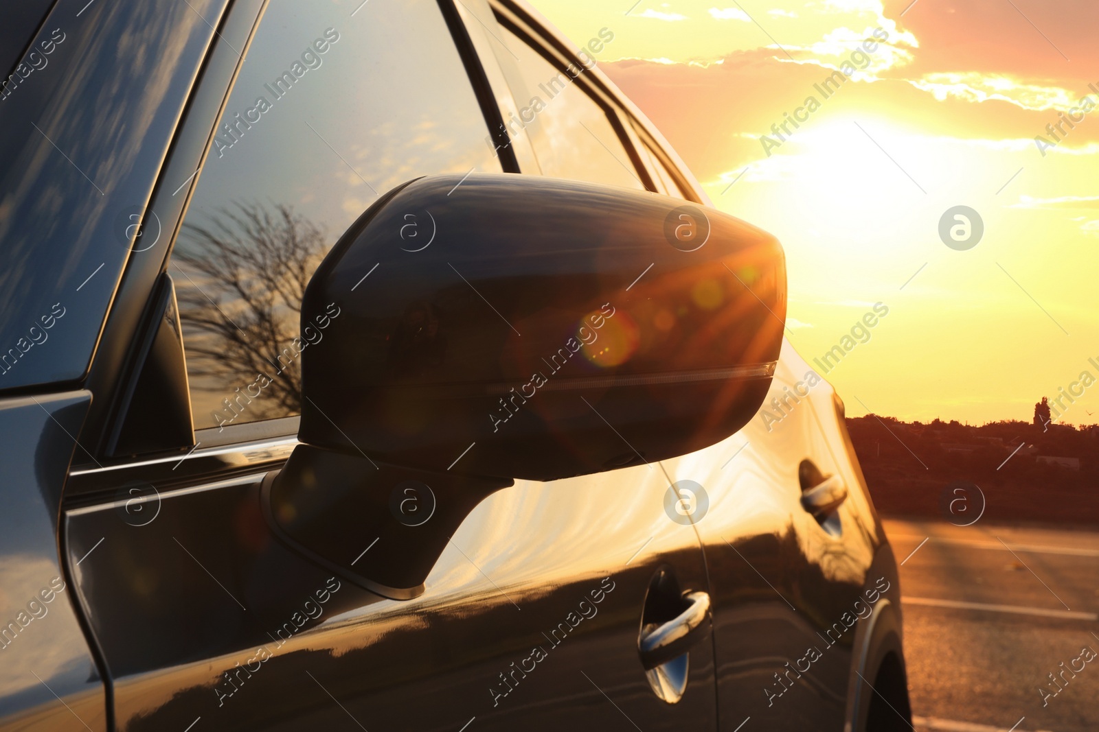 Black modern car parked on road at sunset, closeup of side view mirror Photo of Black modern car parked on road at sunset, closeup of side view mirror