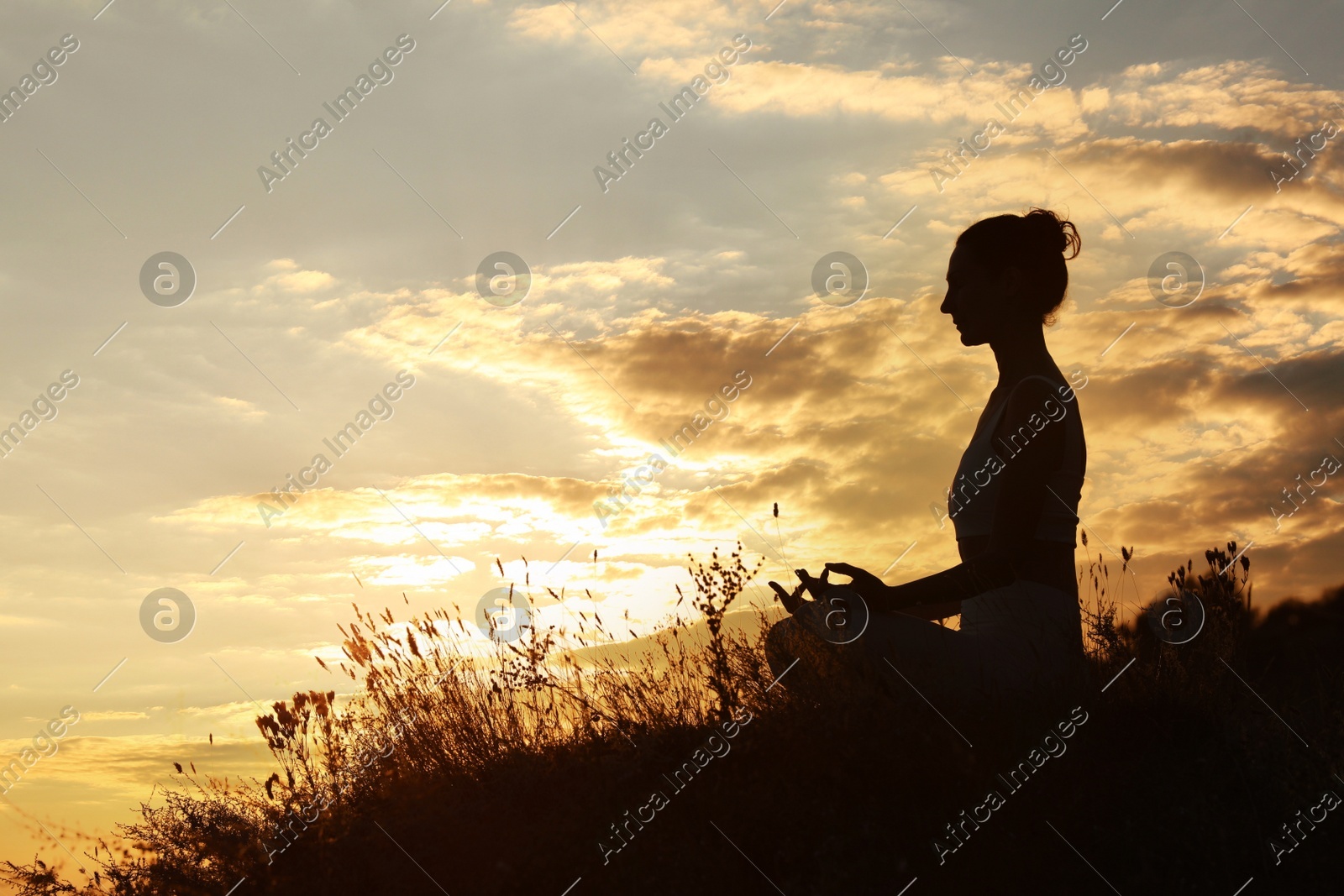 Silhouette of woman meditating outdoors at sunset. Space for text Photo of Silhouette of woman meditating outdoors at sunset. Space for text