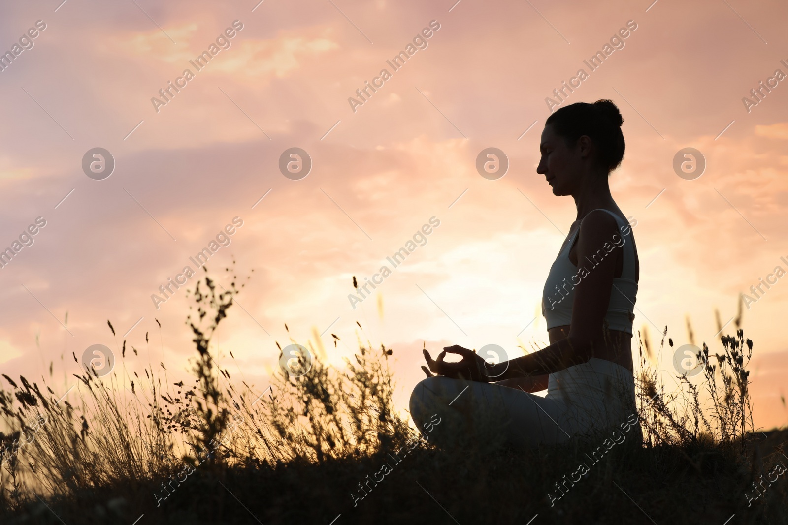 Mature woman meditating outdoors at sunset. Space for text Photo of Mature woman meditating outdoors at sunset. Space for text