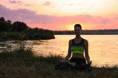 Mature woman meditating near river at sunset. Space for text Photo of Mature woman meditating near river at sunset. Space for text