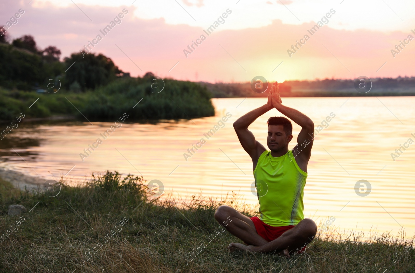 Man meditating near river at sunset. Space for text Photo of Man meditating near river at sunset. Space for text