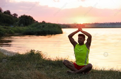 Man meditating near river at sunset. Space for text Photo of Man meditating near river at sunset. Space for text