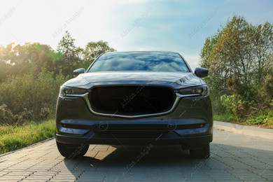 Black modern car on paved road at sunset Photo of Black modern car on paved road at sunset