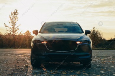 Black modern car parked on road at sunset Photo of Black modern car parked on road at sunset
