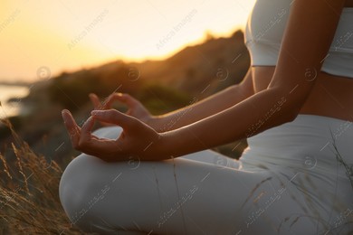 Woman meditating outdoors at sunset, closeup view Photo of Woman meditating outdoors at sunset, closeup view
