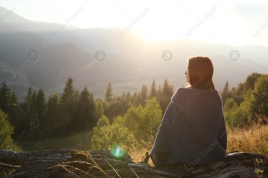 Woman with cozy plaid enjoying sunset in mountains, back view Photo of Woman with cozy plaid enjoying sunset in mountains, back view