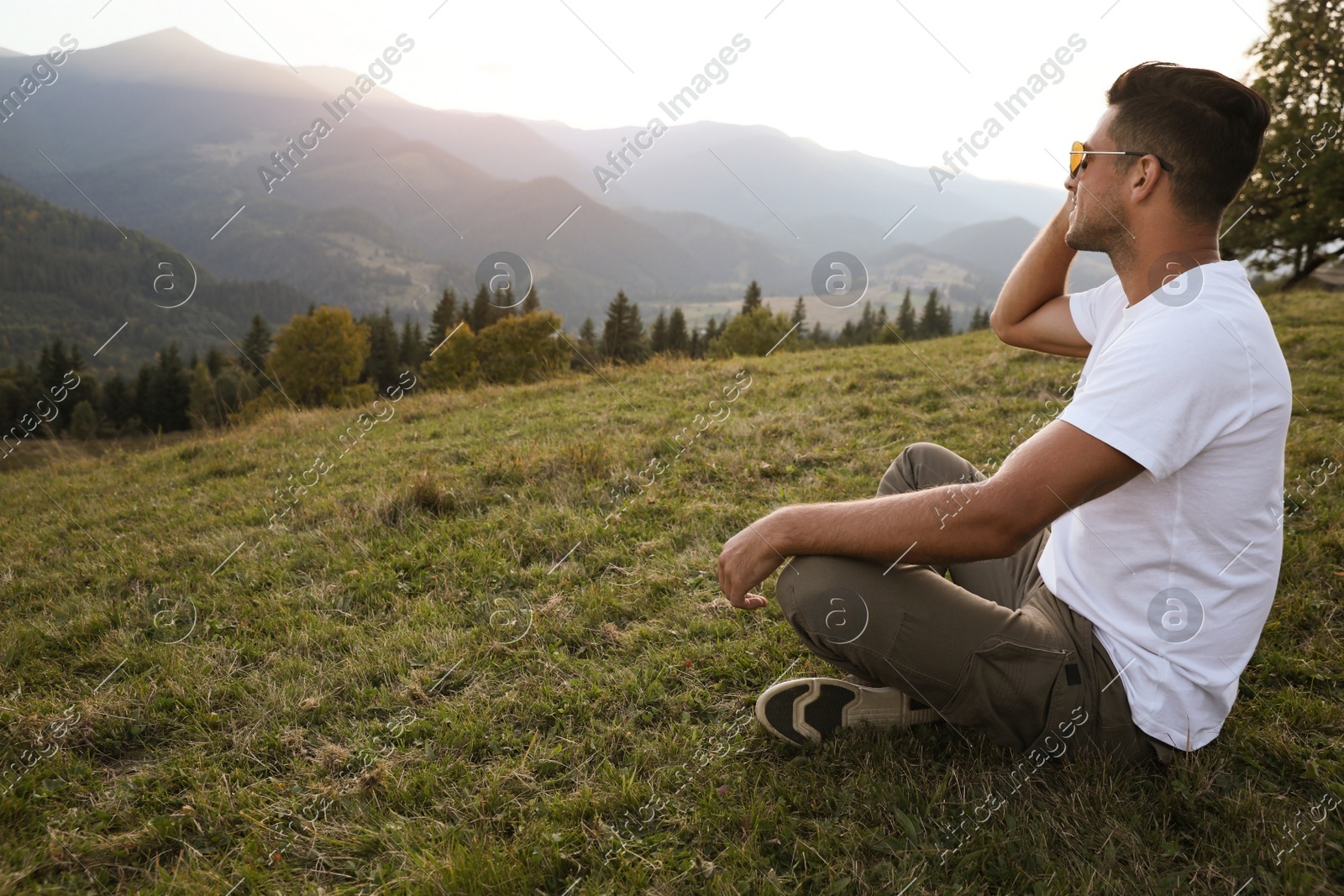 Handsome man enjoying beautiful mountain landscape at sunset Photo of Handsome man enjoying beautiful mountain landscape at sunset