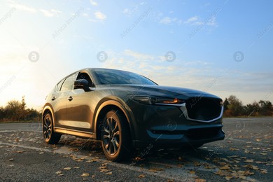 Black modern car parked on road at sunset Photo of Black modern car parked on road at sunset