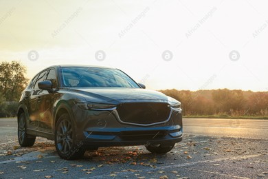 Black modern car parked on road at sunset Photo of Black modern car parked on road at sunset
