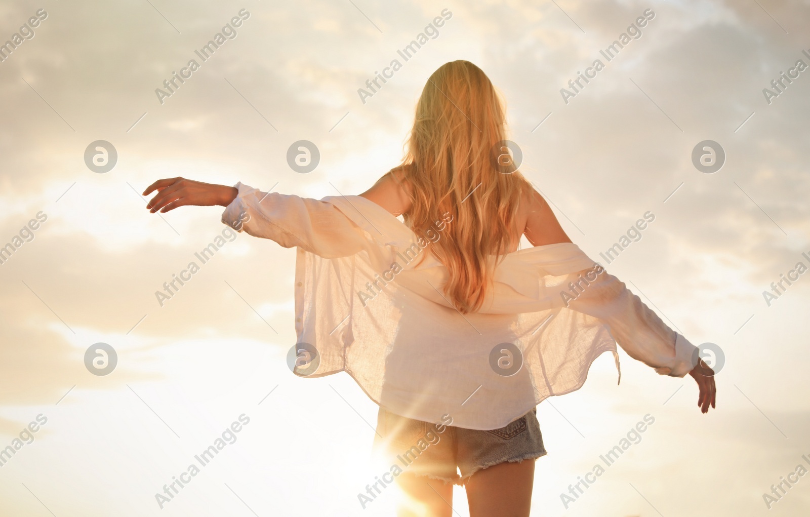 Young woman outdoors at sunset, back view Photo of Young woman outdoors at sunset, back view