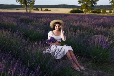 Beautiful young woman sitting in lavender field at sunset Photo of Beautiful young woman sitting in lavender field at sunset