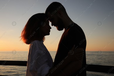 Happy young couple hugging on sea embankment at sunset Photo of Happy young couple hugging on sea embankment at sunset