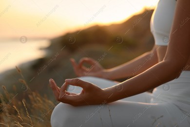 Woman meditating outdoors at sunset, closeup view Photo of Woman meditating outdoors at sunset, closeup view