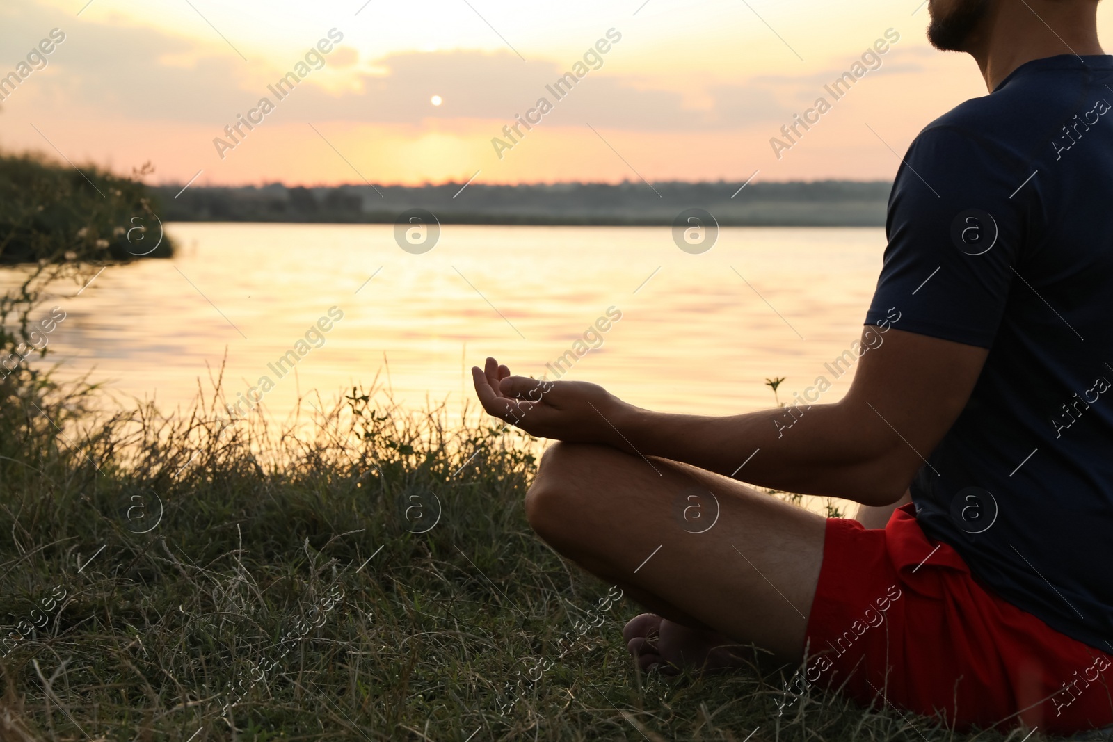 Man meditating near river at sunset, closeup. Space for text Photo of Man meditating near river at sunset, closeup. Space for text