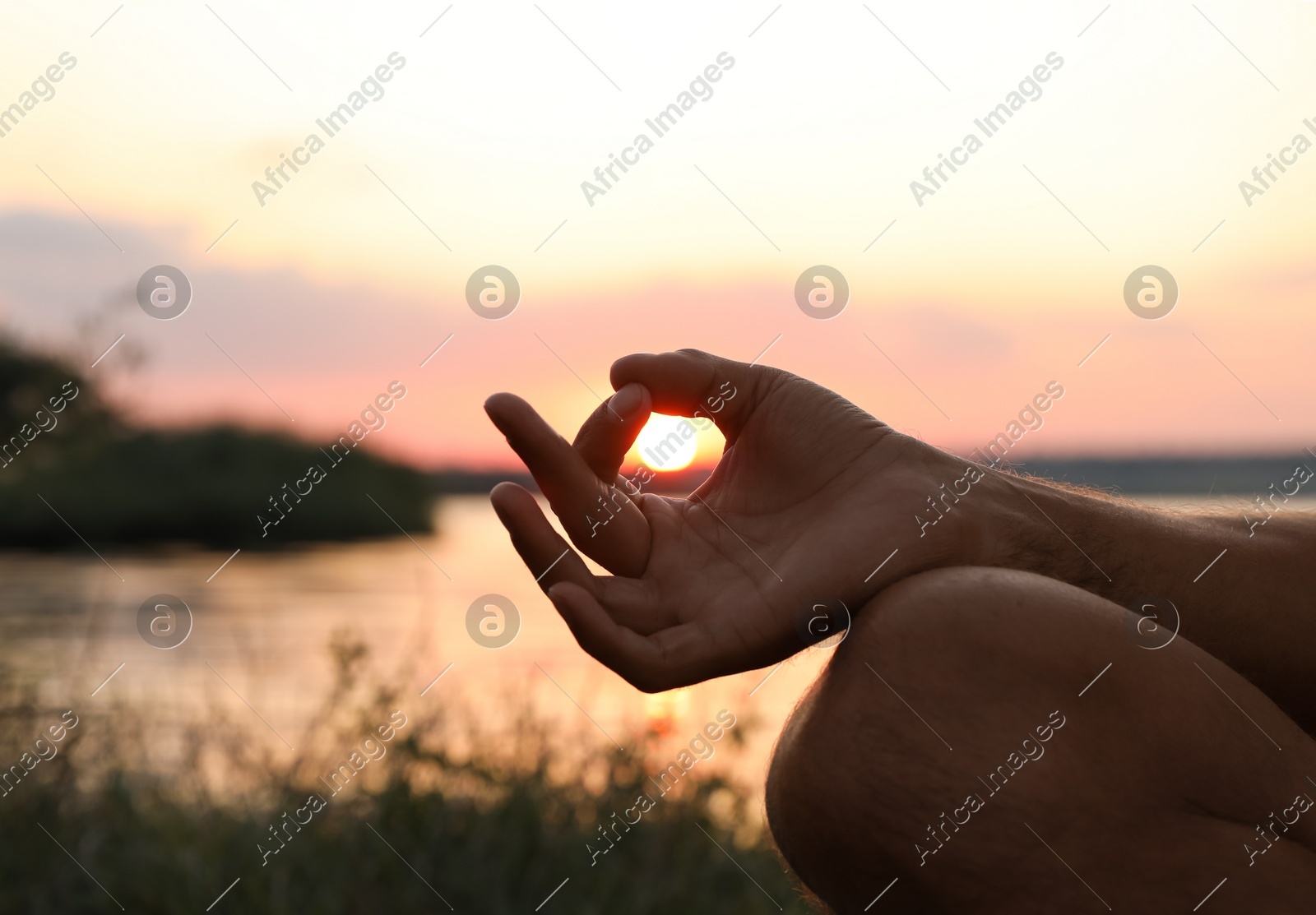 Man meditating near river at sunset, closeup. Space for text Photo of Man meditating near river at sunset, closeup. Space for text